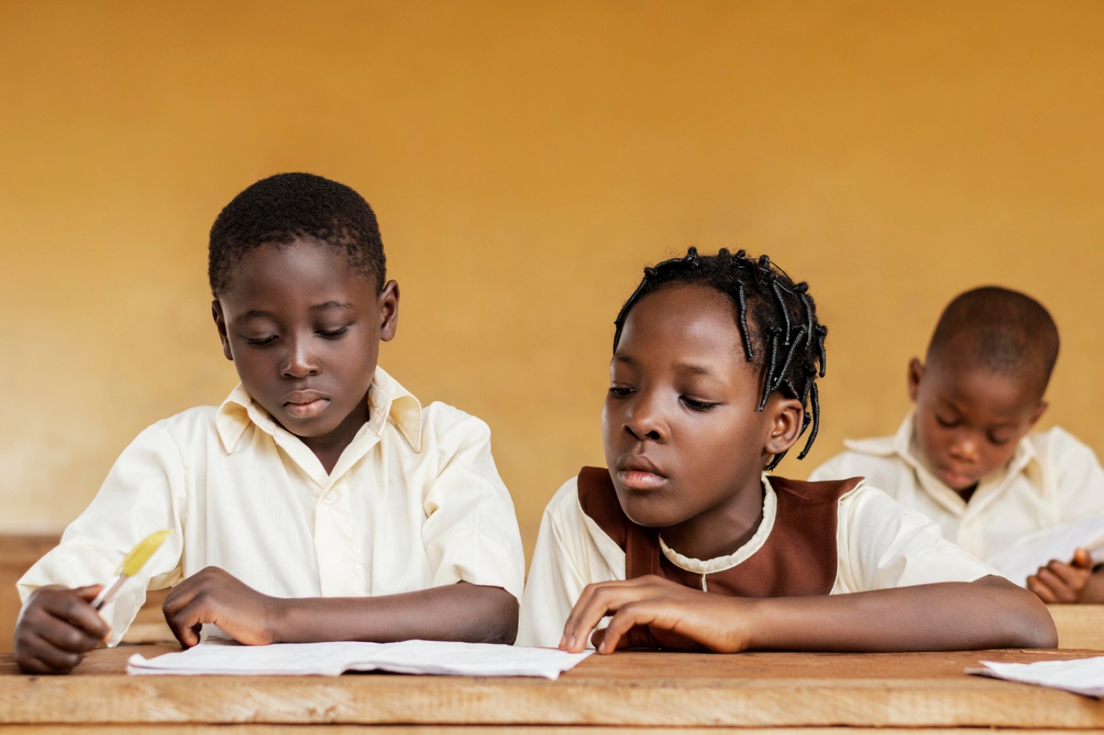 Three pupils working together at a wooden desk
