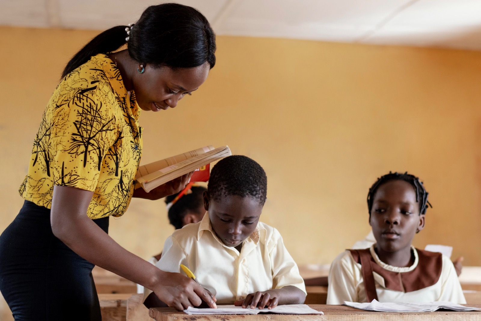 A teacher leaning in to help a pupil with their work