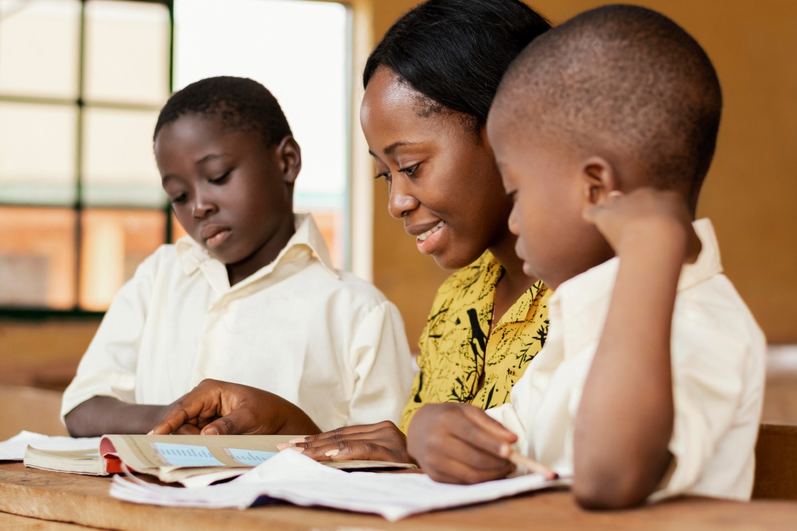 A teacher reading with two pupils